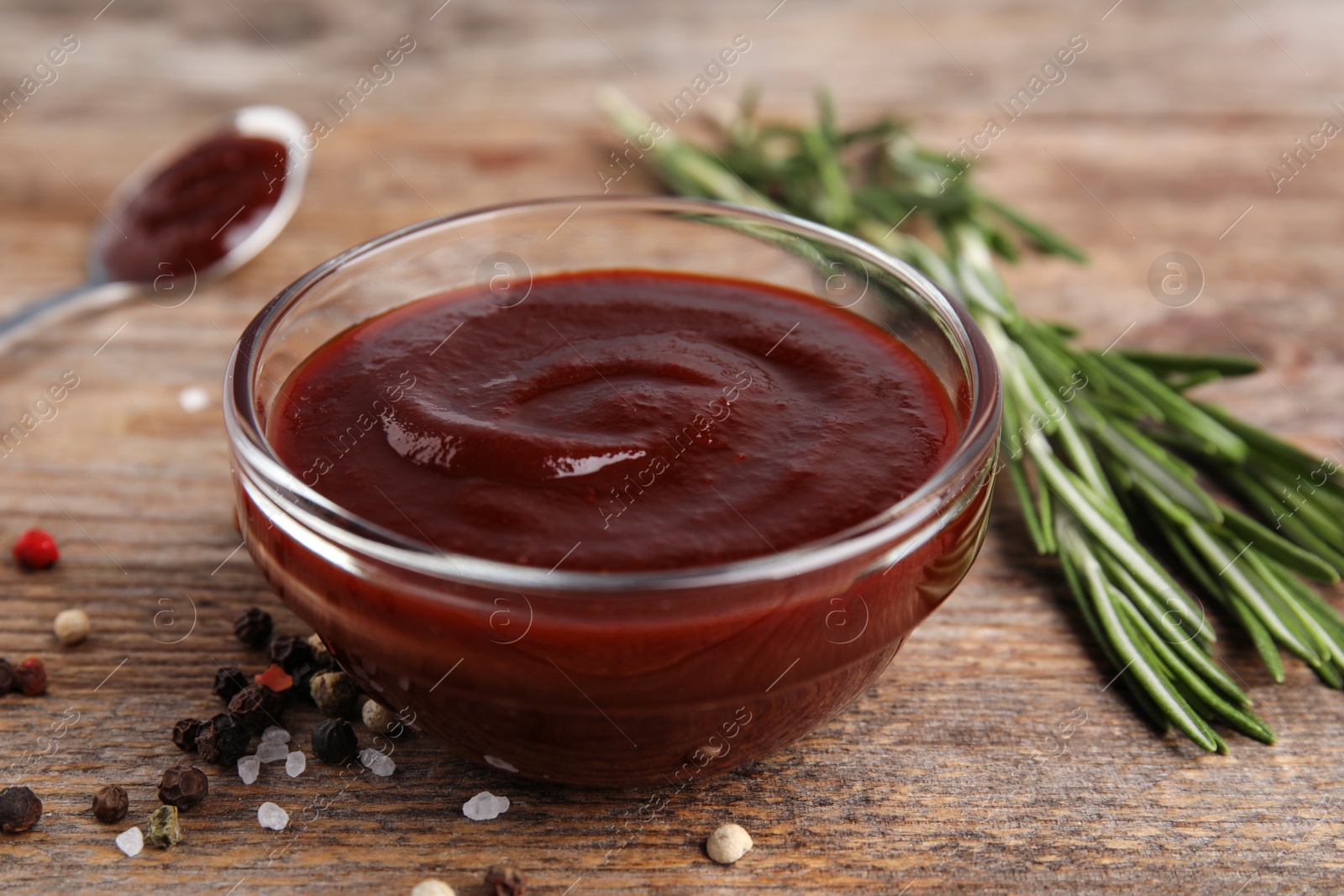 Photo of Composition with bowl of barbecue sauce on wooden table