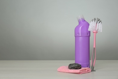 Photo of Bottle of cleaning product and supplies on light table. Space for text