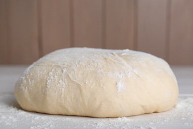 Fresh yeast dough with flour on white wooden table, closeup