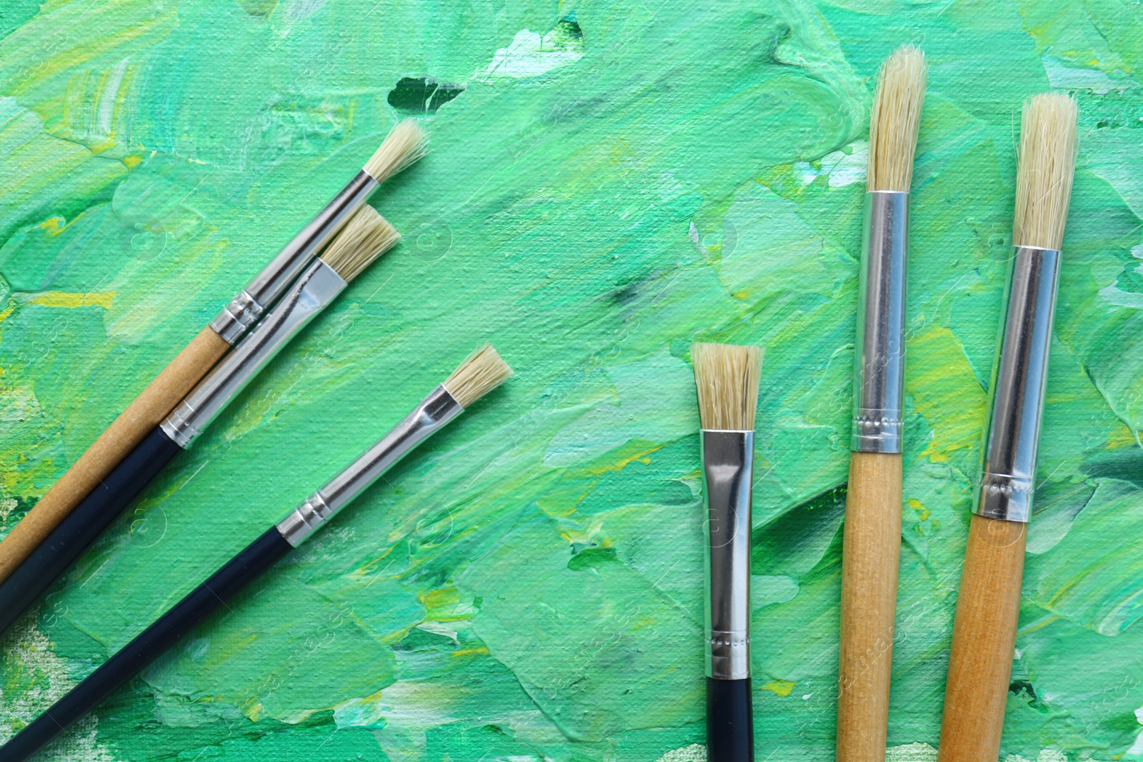 Photo of Set of different brushes on abstract colorful paint, flat lay