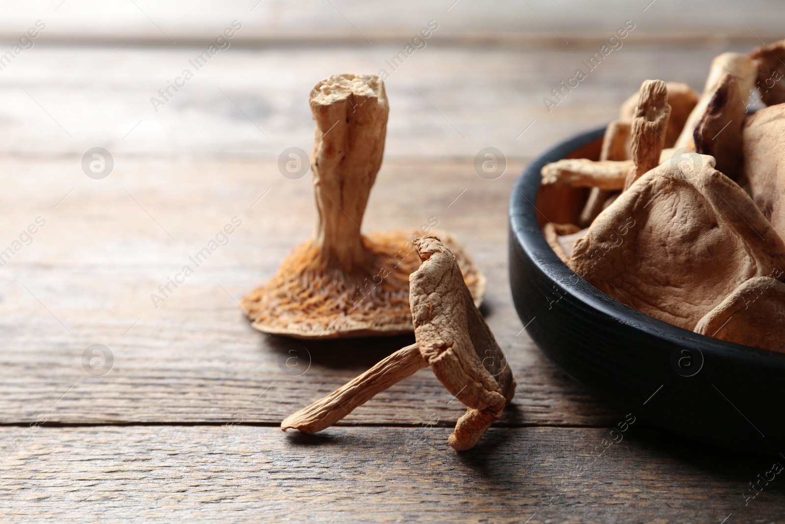 Photo of Composition of dried mushrooms and plate on wooden background