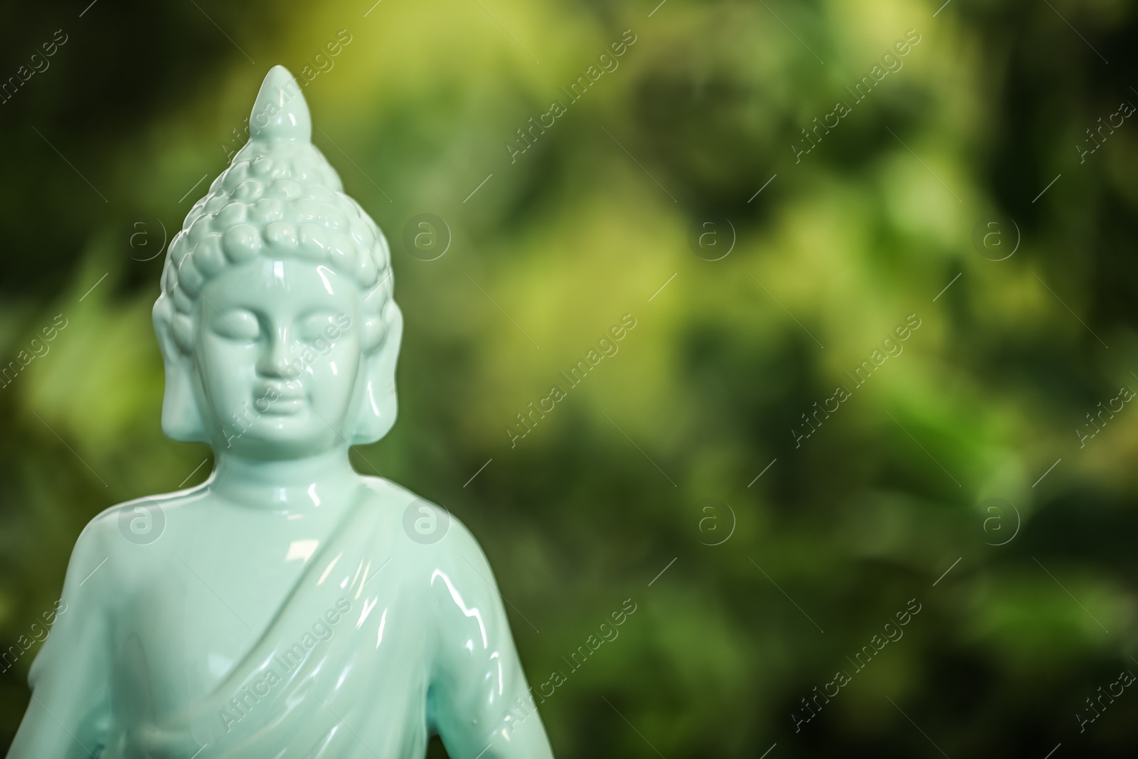 Photo of Buddha statue against blurred green background, closeup. Space for text