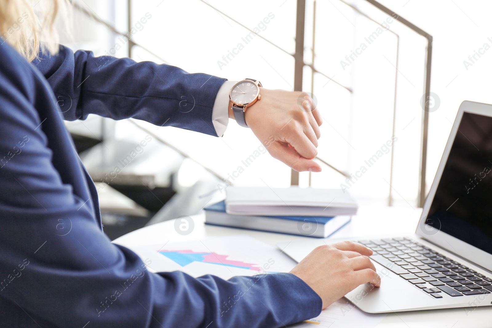 Photo of Young businesswoman checking time on her wristwatch at workplace. Time management