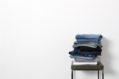 Photo of Stack of different jeans on table against white background. Space for text