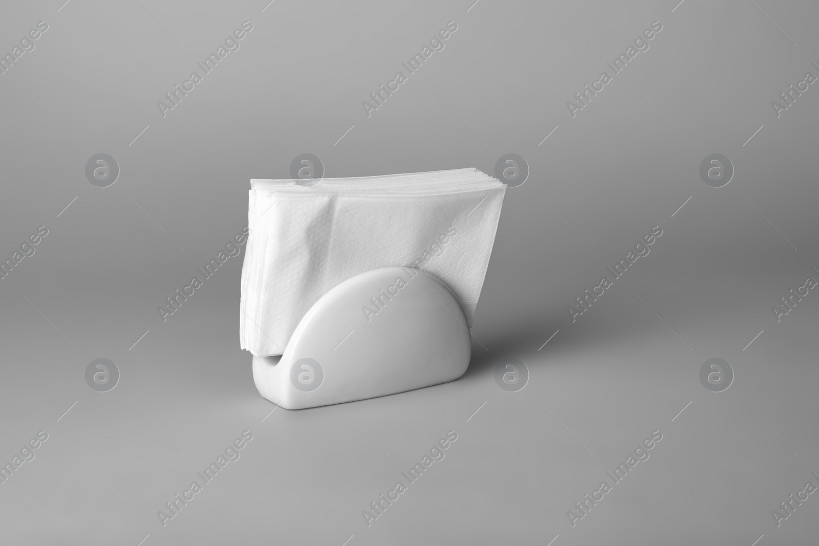 Photo of Ceramic napkin holder with paper serviettes on gray background