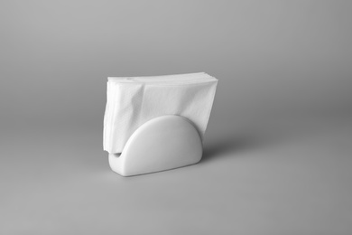 Photo of Ceramic napkin holder with paper serviettes on gray background