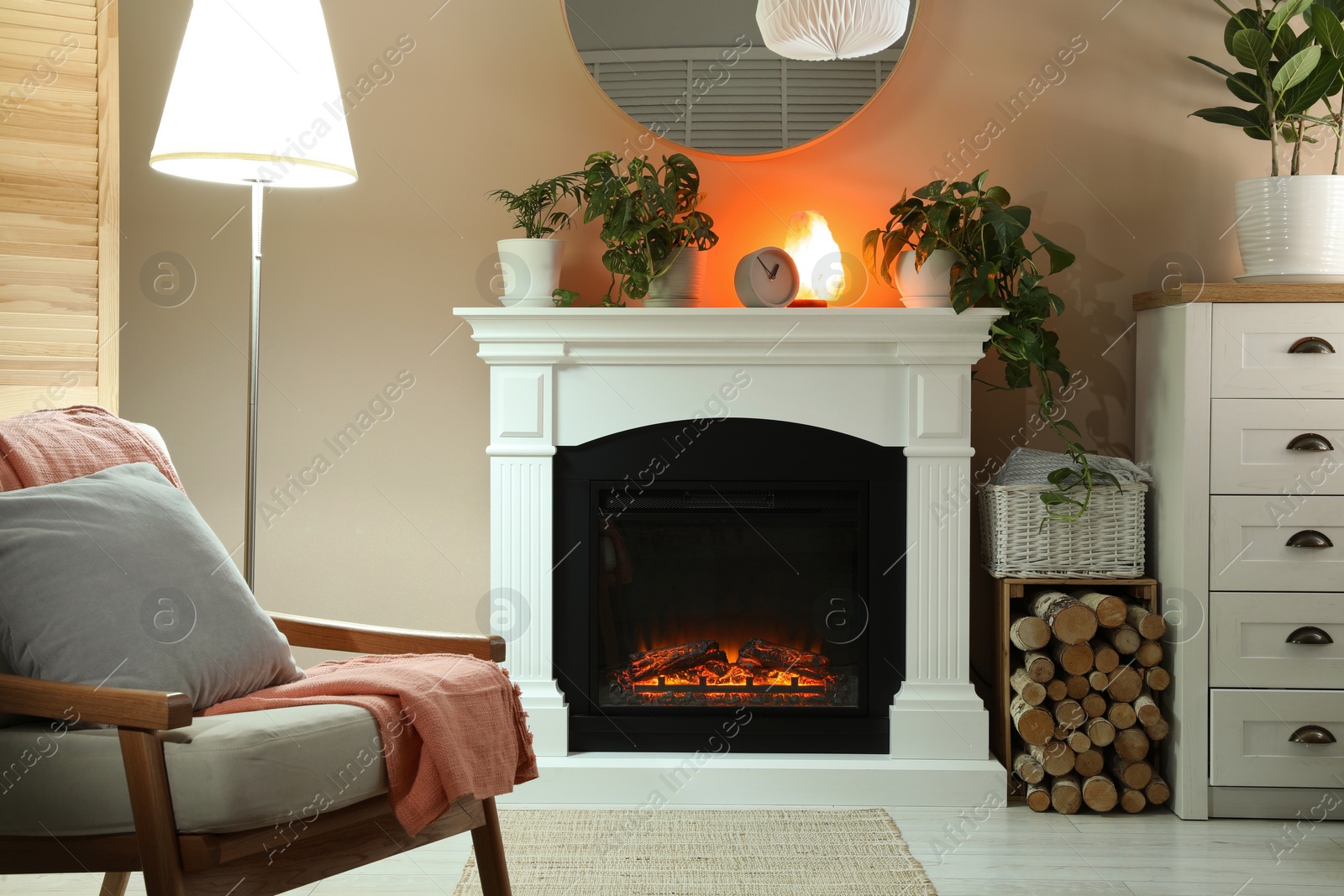 Photo of Stylish fireplace near comfortable armchair in cosy living room. Interior design