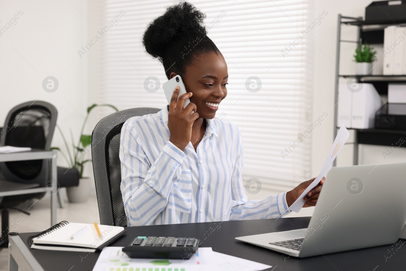 Photo of Professional accountant talking on phone and working at desk in office