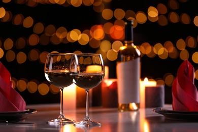 Romantic table setting with glasses of wine and burning candles against blurred background
