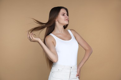 Young woman with strong healthy hair on beige background