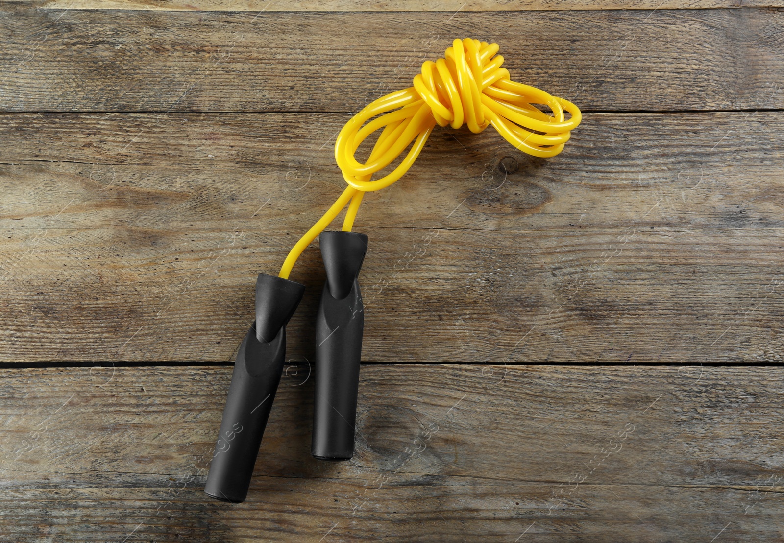 Photo of Skipping rope on wooden table, top view. Sports equipment