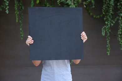 Woman holding blank poster outdoors. Mockup for design