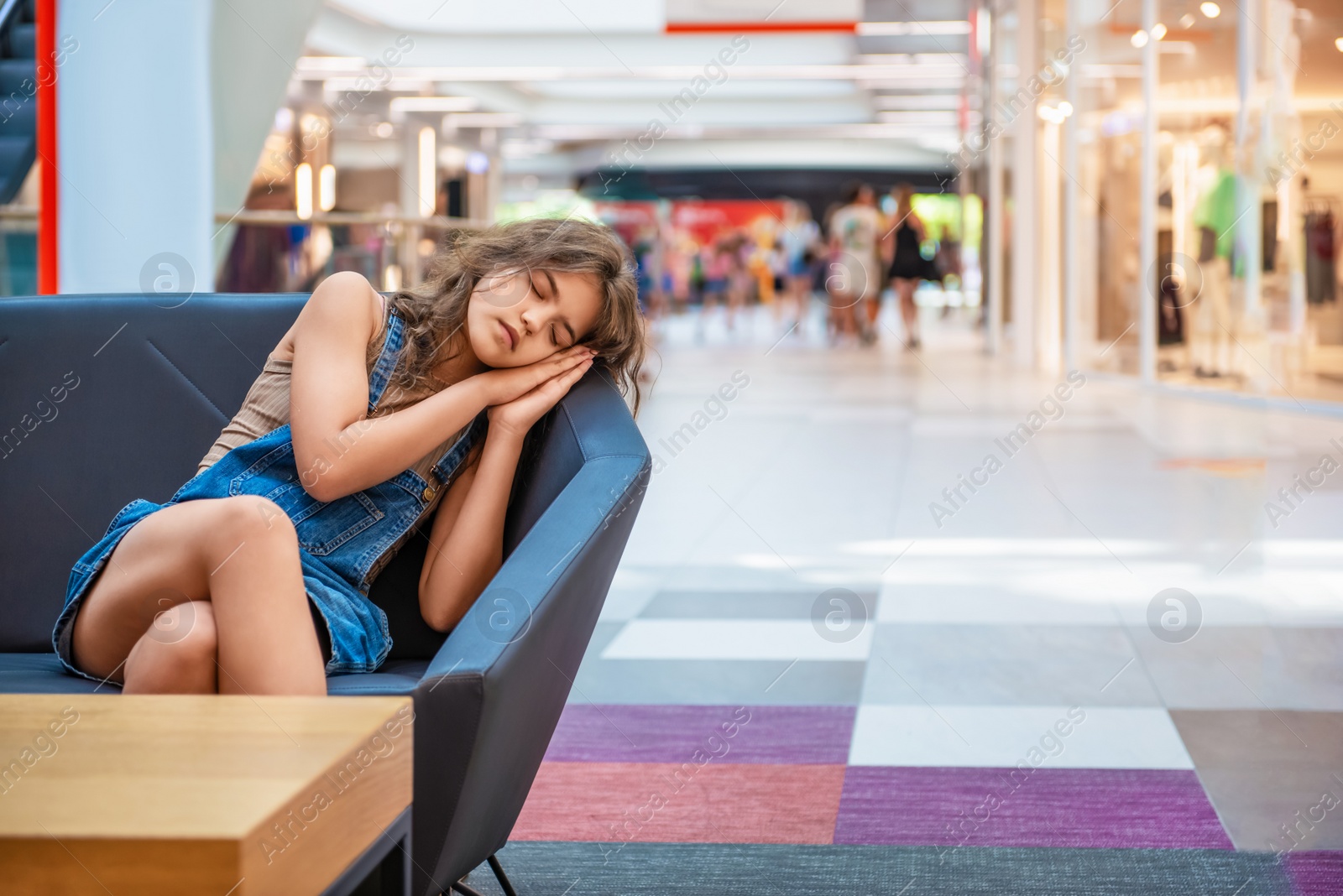 Photo of Tired teenage girl sleeping on sofa in shopping mall