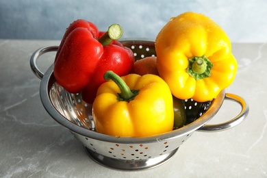 Photo of Colander with ripe paprika peppers on table