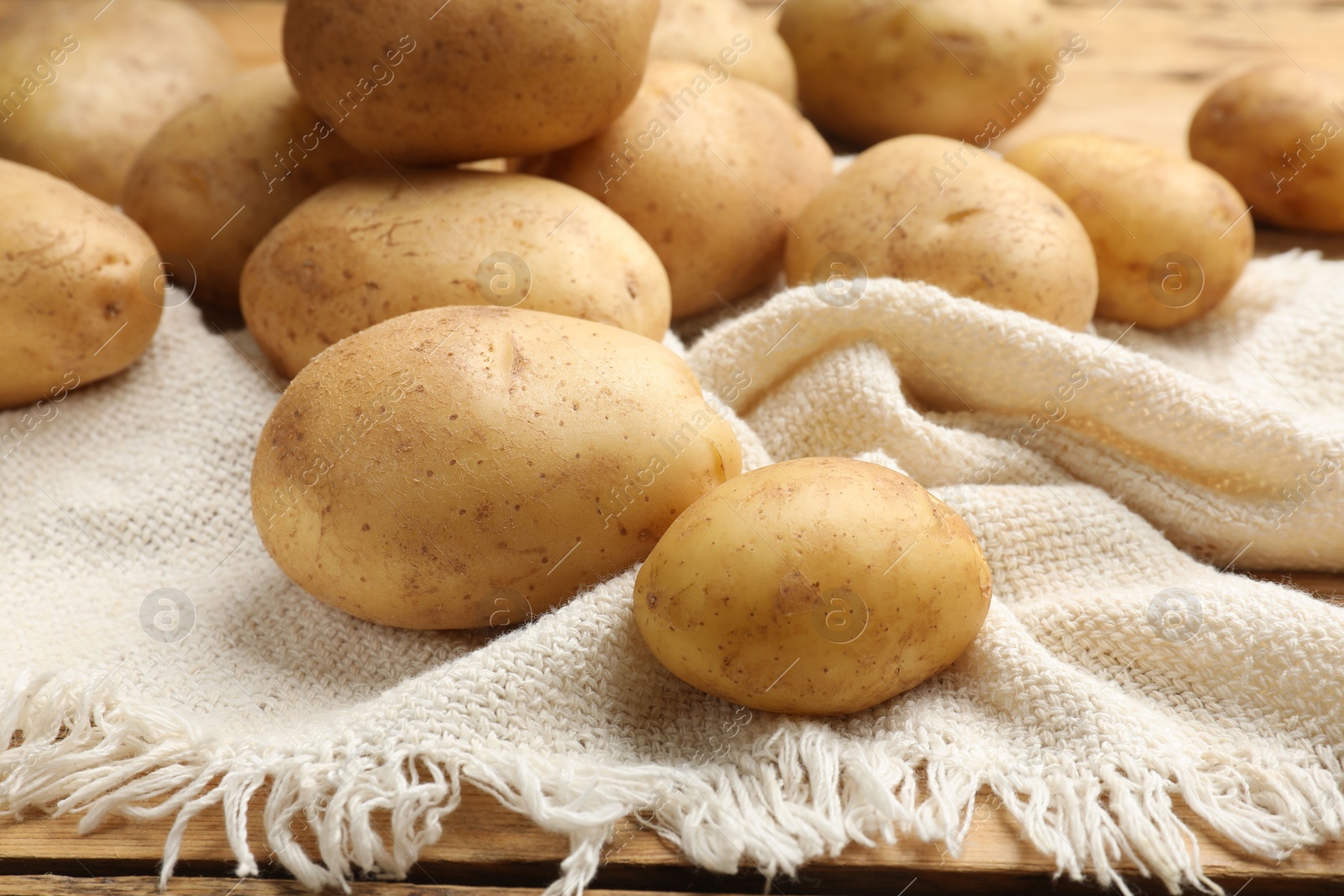 Photo of Raw fresh potatoes and napkin on wooden table