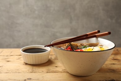 Bowl of delicious ramen and chopsticks on wooden table. Noodle soup