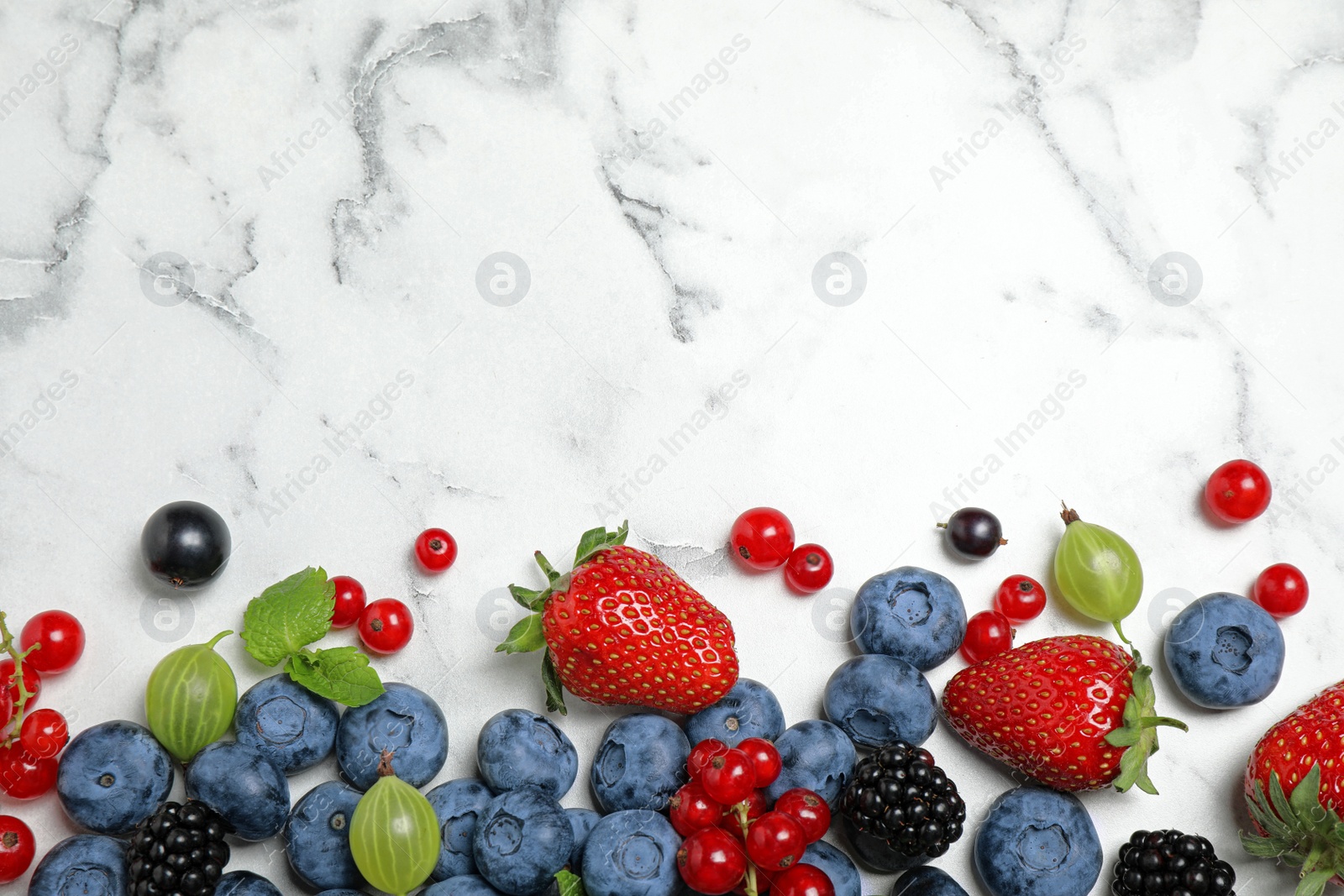 Photo of Mix of fresh berries on white marble table, flat lay. Space for text