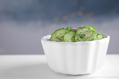 Bowl of tasty cucumber salad on table. Space for text