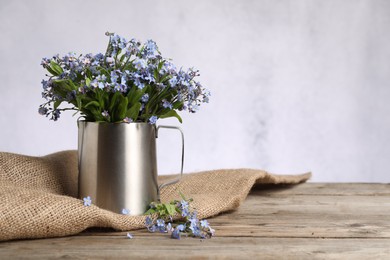 Beautiful forget-me-not flowers on wooden table against light background. Space for text