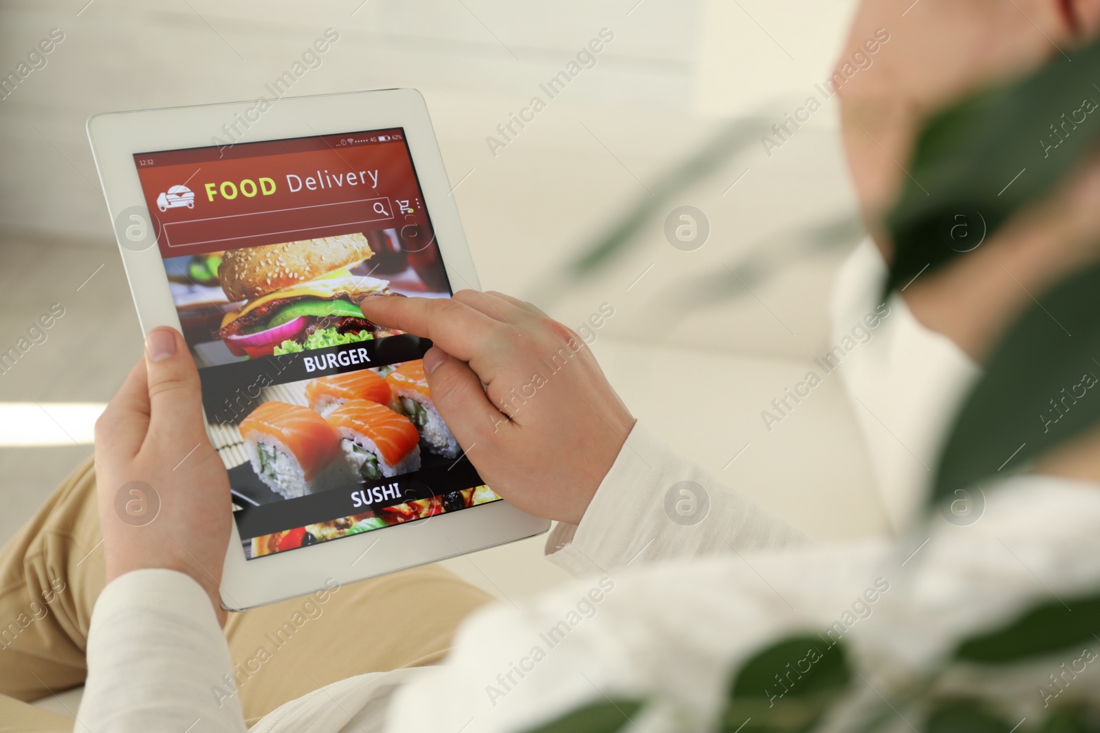 Photo of Man using tablet for ordering food online at home, closeup. Delivery service