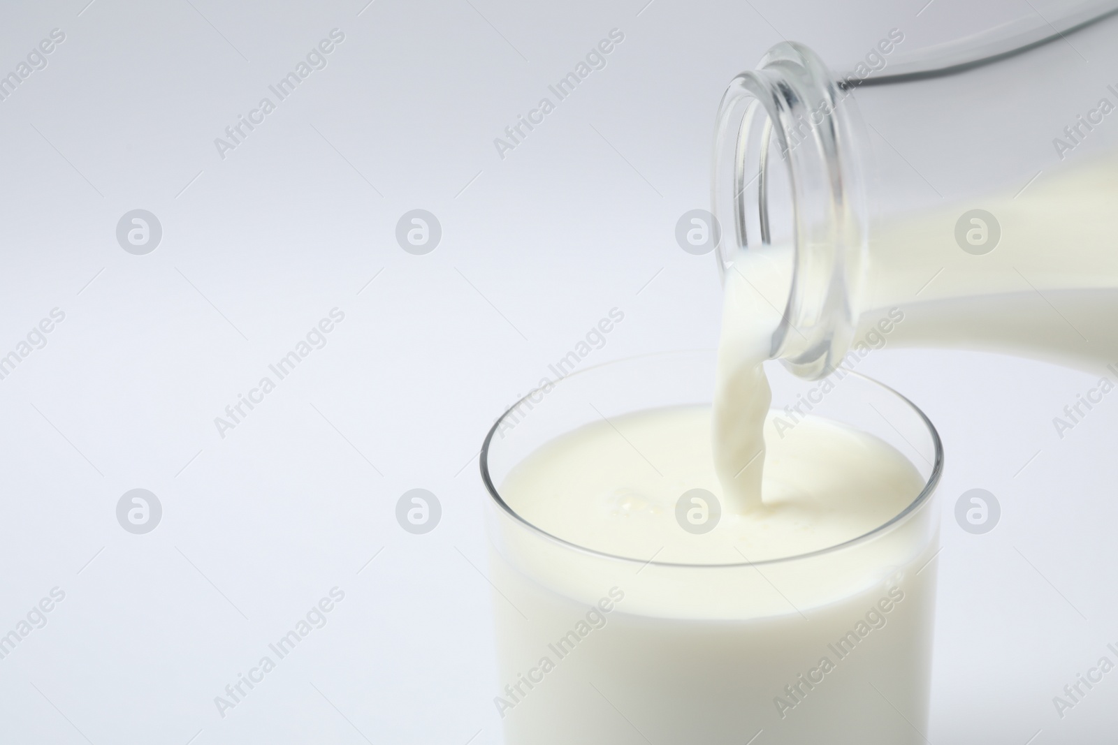 Photo of Pouring milk into glass on white background, closeup