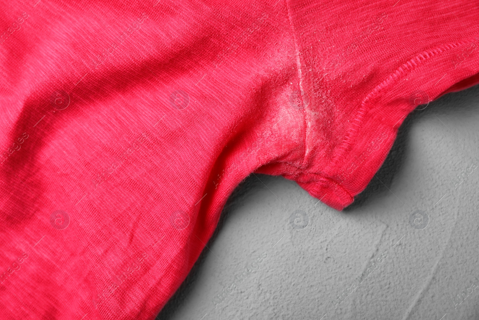 Photo of T-shirt with deodorant stain on grey background, closeup