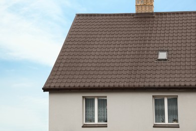 Beautiful house with brown roof against blue sky