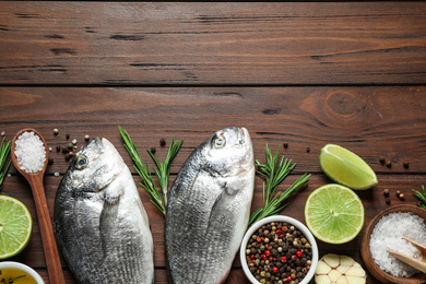 Flat lay composition with raw dorada fish on wooden table, space for text