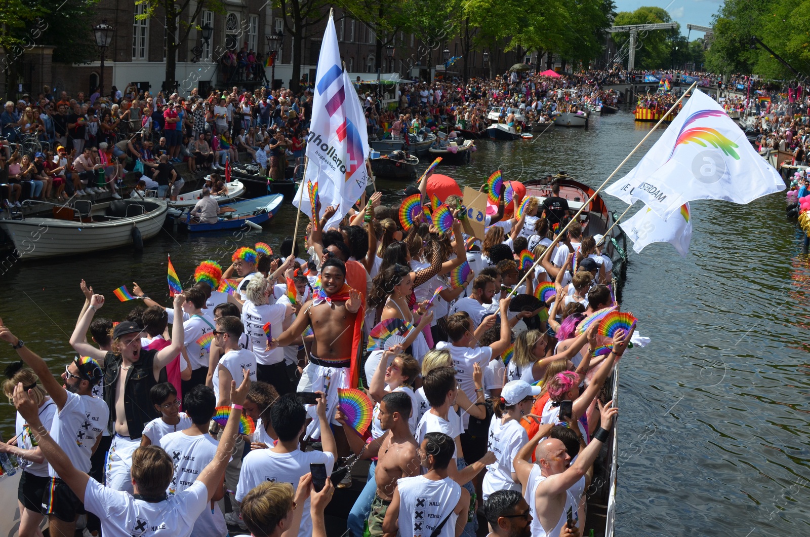 Photo of AMSTERDAM, NETHERLANDS - AUGUST 06, 2022: Many people in boats at LGBT pride parade on river