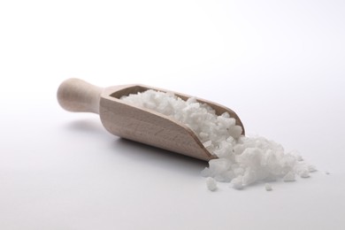 Photo of Natural salt in wooden scoop on white background