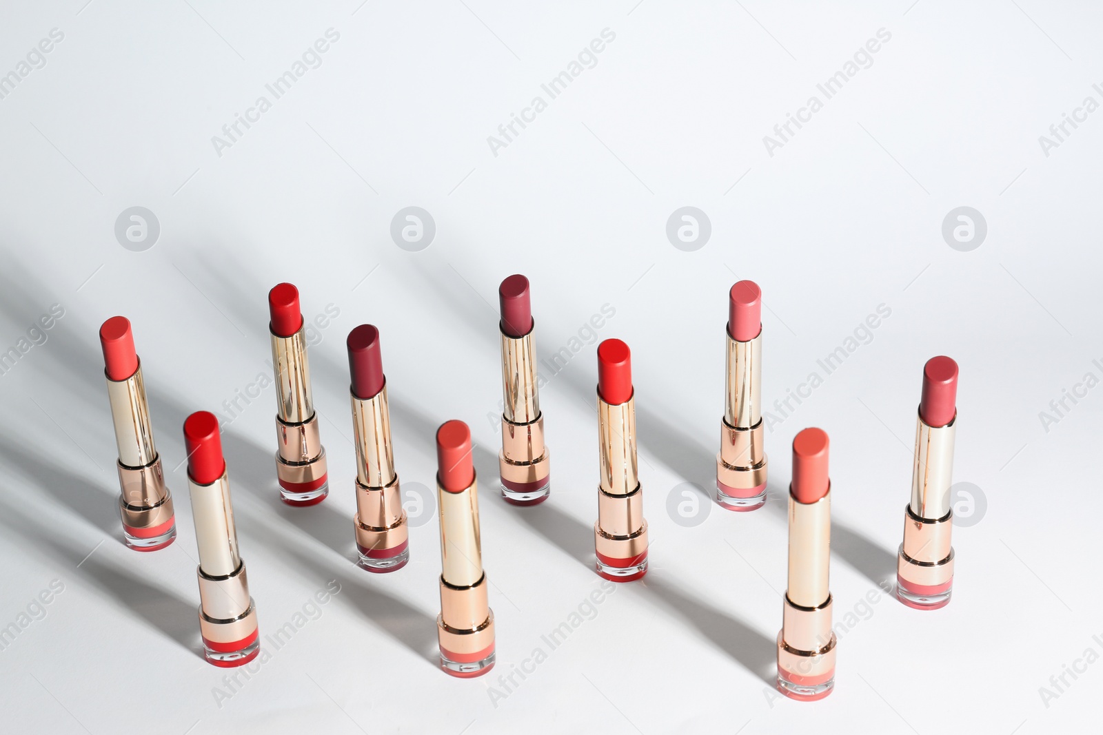 Photo of Set of bright lipsticks in gold tubes on white background