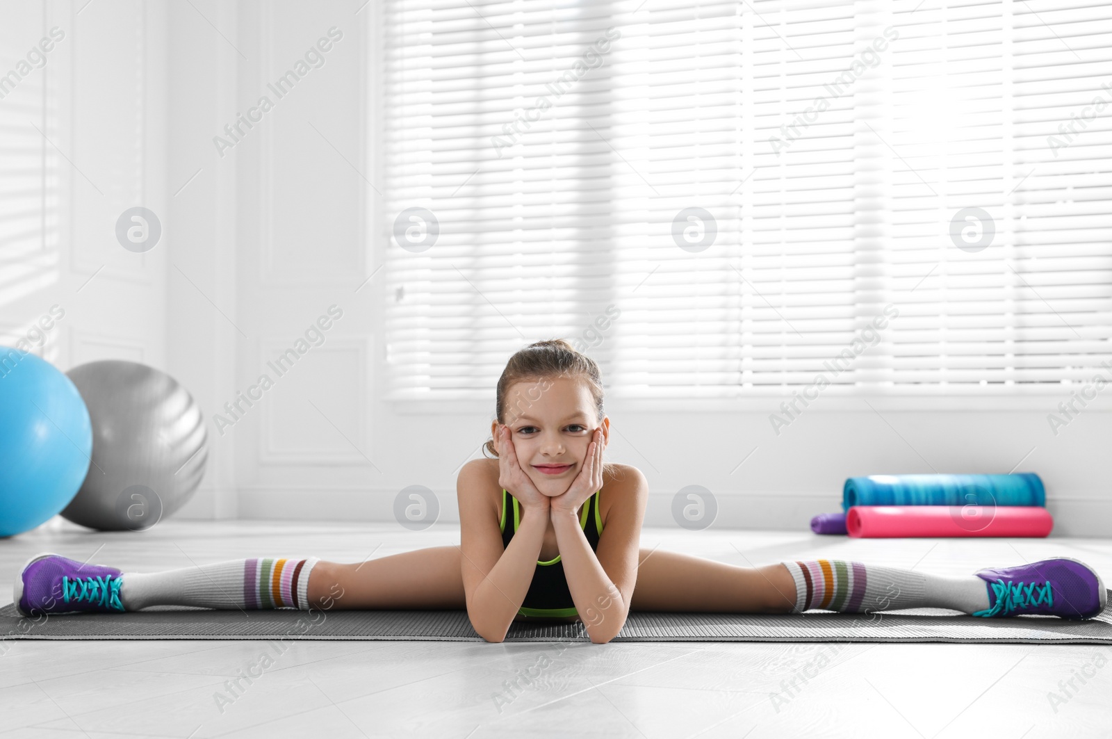 Photo of Cute little girl doing gymnastic exercise indoors. Side split