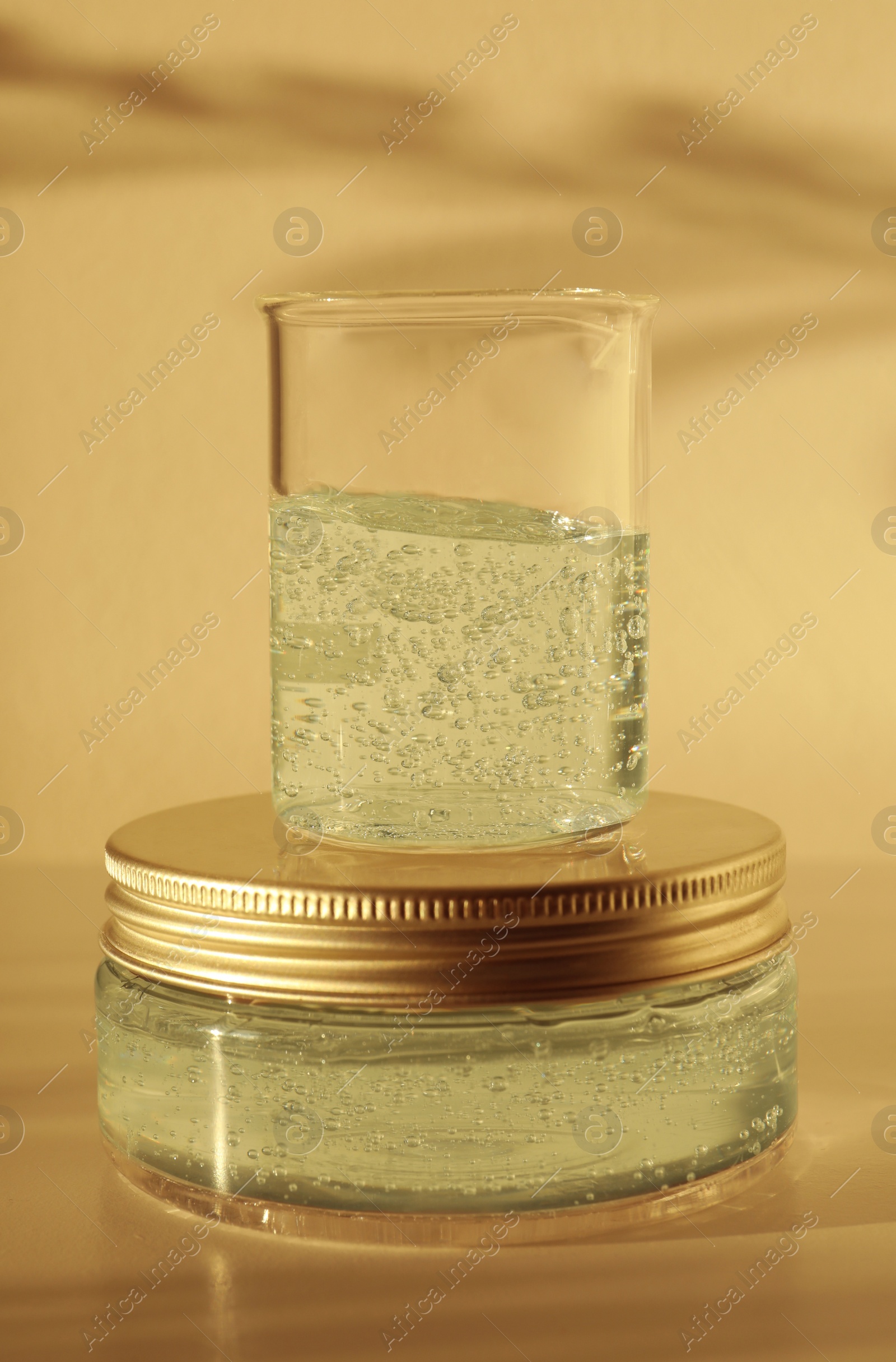 Photo of Jar and glass beaker with cosmetic gel on light background