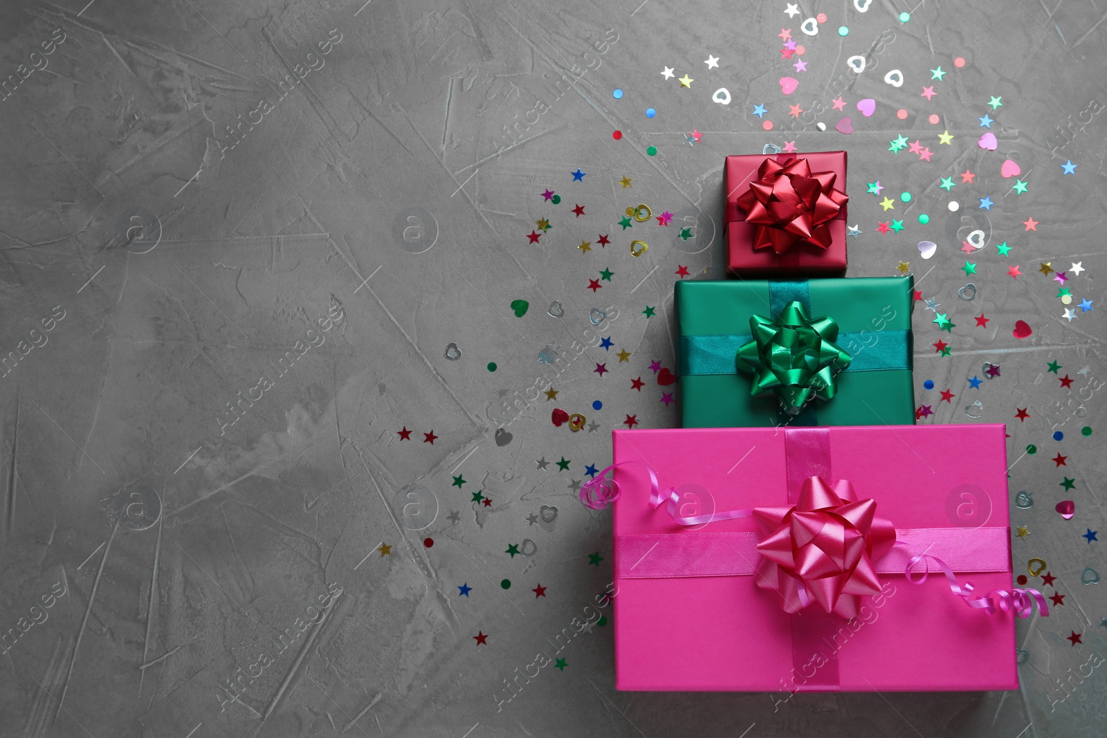 Photo of Gift boxes and shiny confetti on grey background, flat lay. Space for text