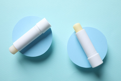 Photo of Hygienic lipsticks on turquoise background, flat lay