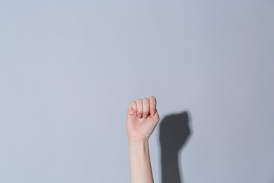 Photo of SOS gesture. Woman showing signal for help on light grey background, closeup