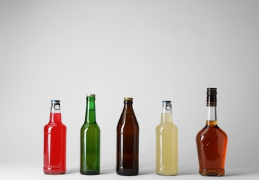 Bottles with different alcoholic drinks on light background