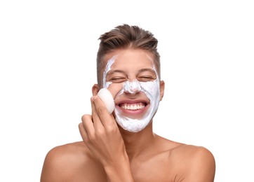 Happy young man washing off face mask with sponge on white background