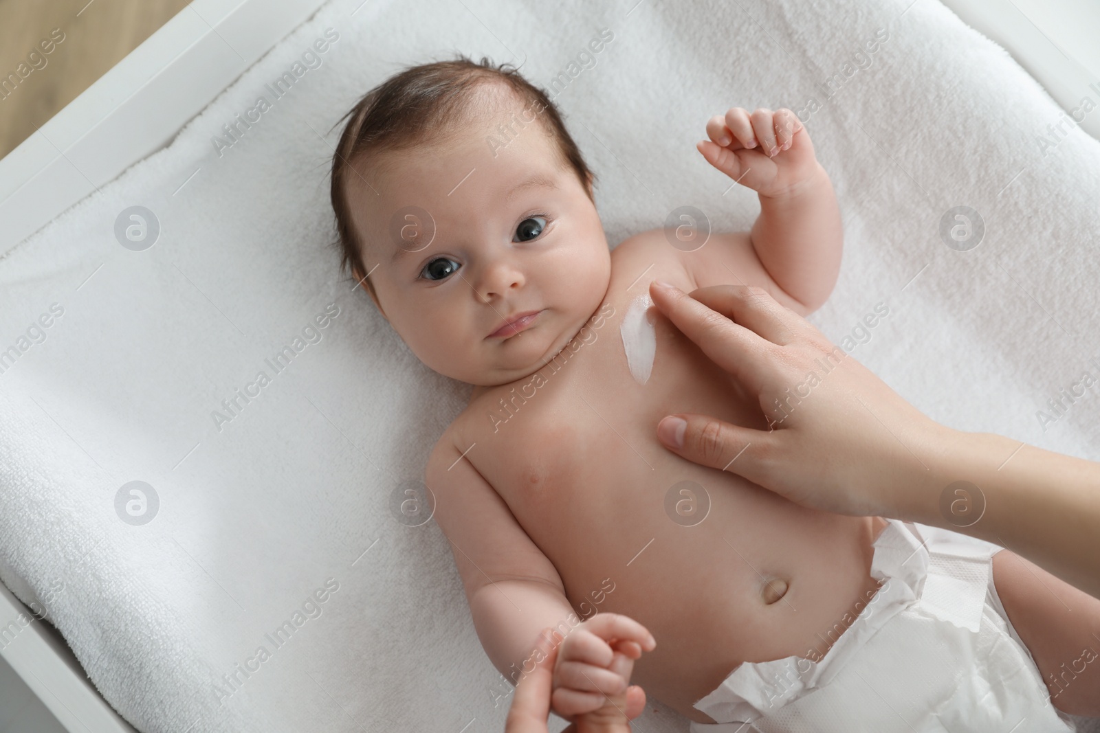 Photo of Mother applying body cream on her little baby, top view