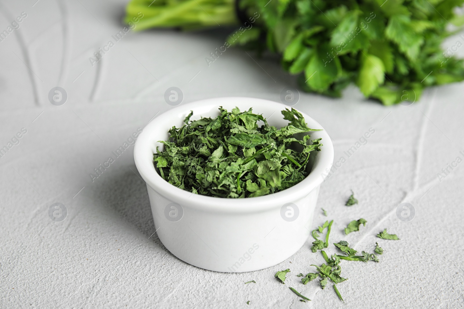 Photo of Bowl of dried parsley on grey stone table