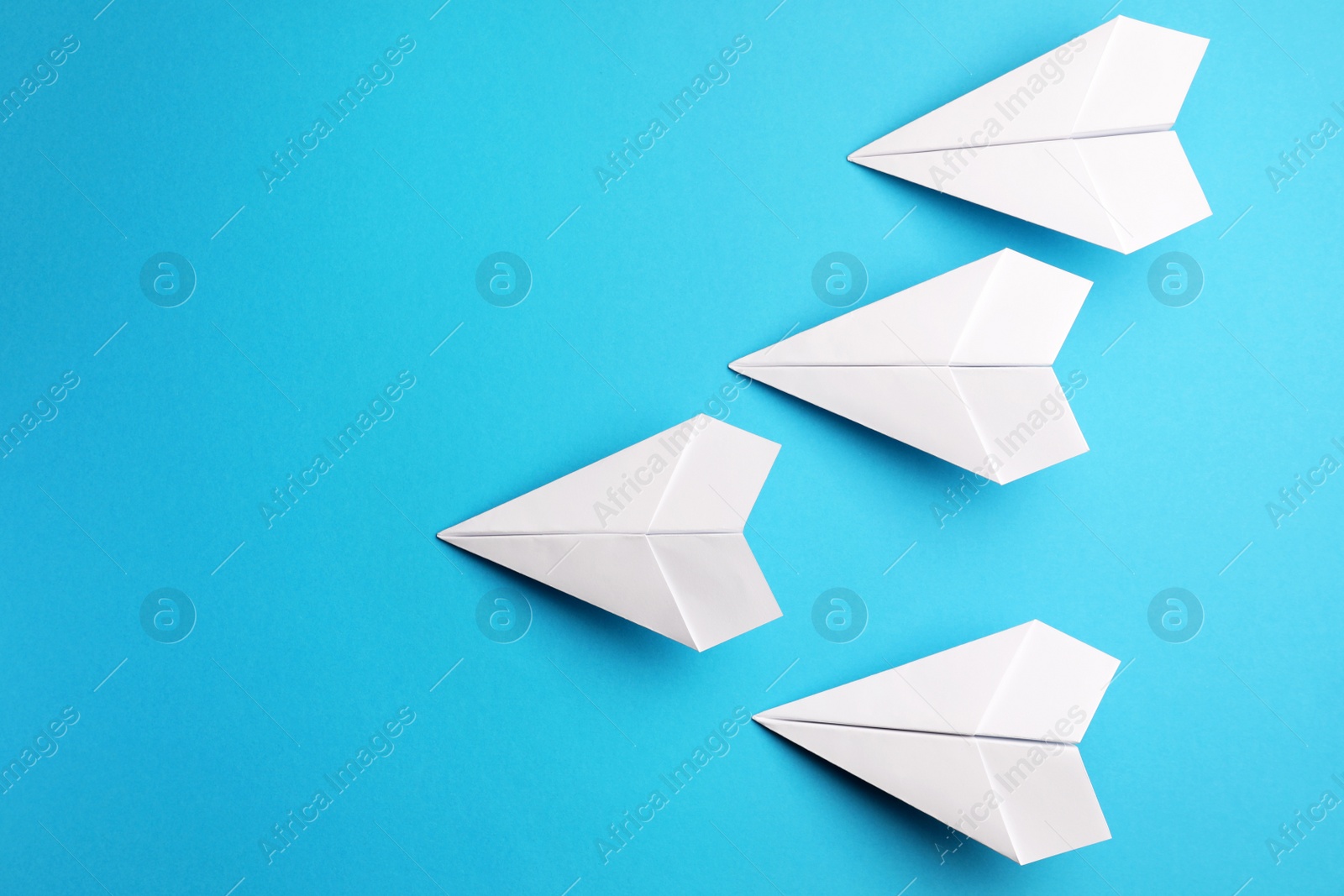 Photo of Handmade white paper planes on light blue background, flat lay. Space for text