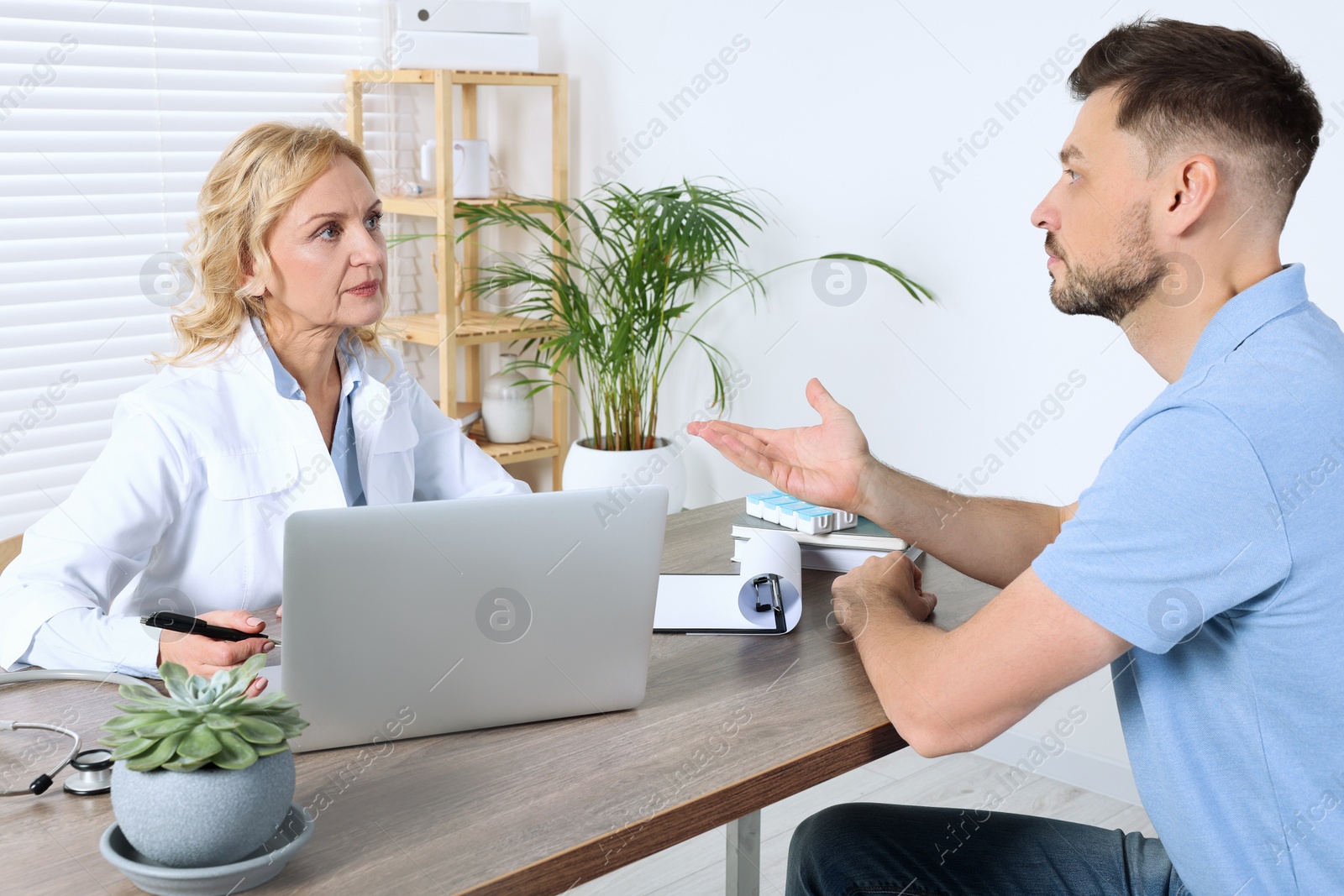 Photo of Doctor consulting patient at table in clinic