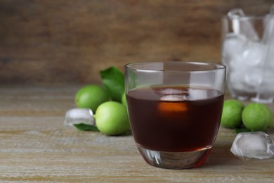 Photo of Delicious liqueur with ice and green walnuts on wooden table. Space for text