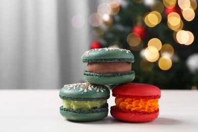 Photo of Different decorated Christmas macarons on white table indoors