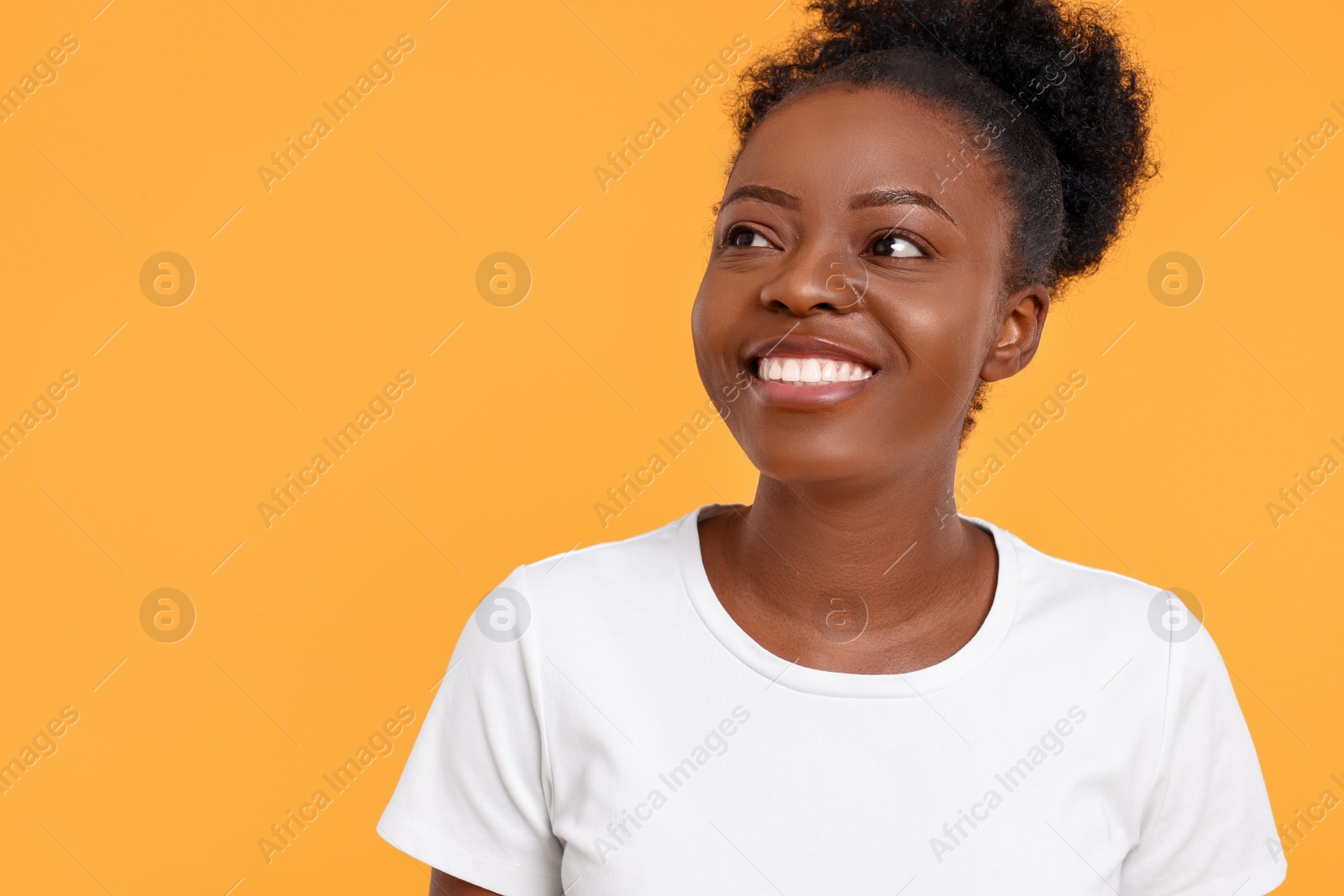Photo of Portrait of happy young woman on orange background. Space for text