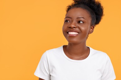 Portrait of happy young woman on orange background. Space for text