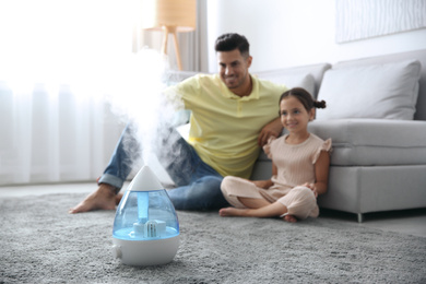 Photo of Father and daughter near modern air humidifier at home
