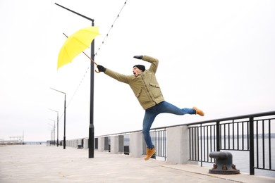 Photo of Man with yellow umbrella caught in gust of wind outdoors