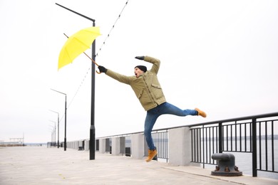 Man with yellow umbrella caught in gust of wind outdoors