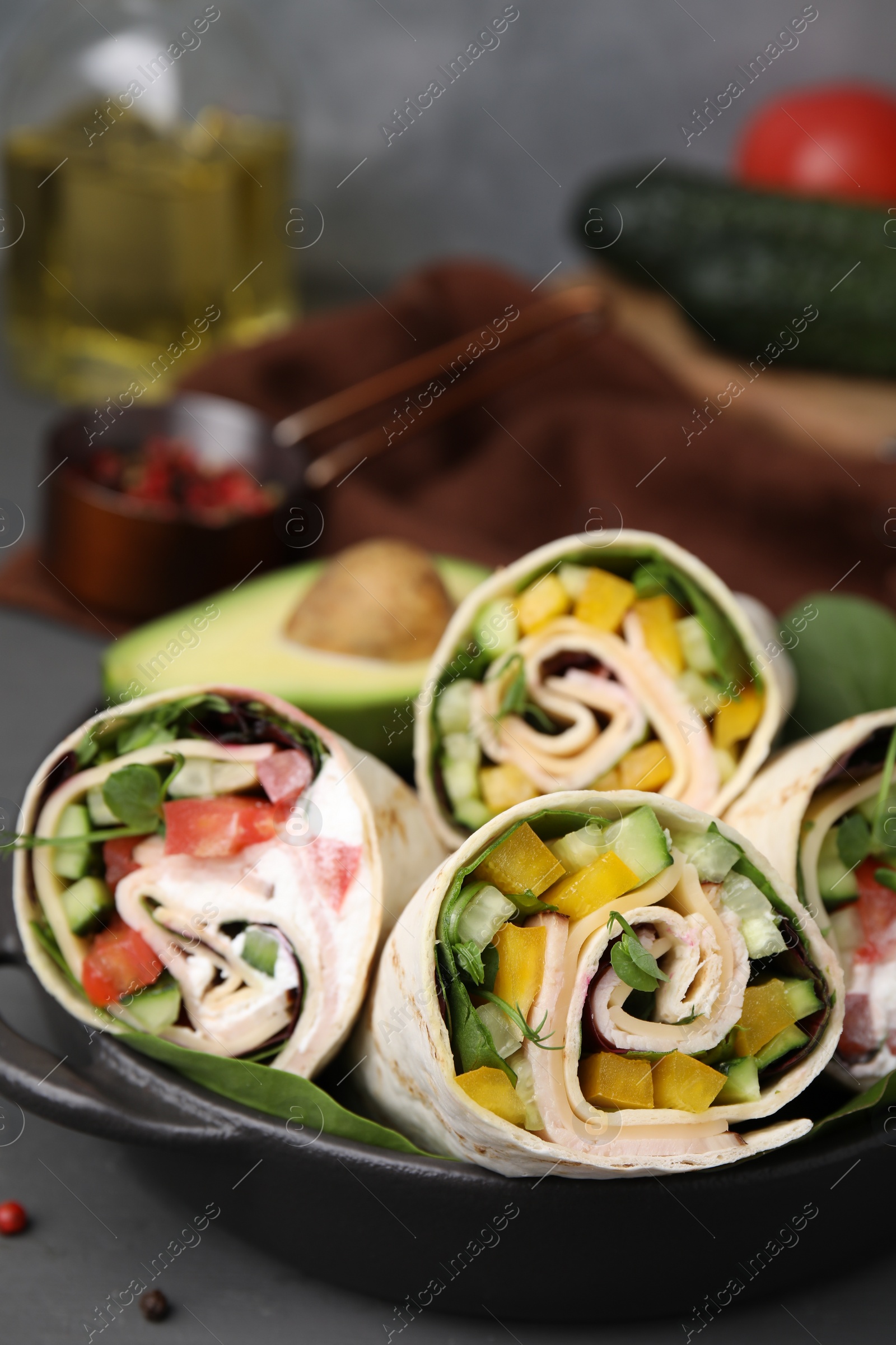 Photo of Delicious sandwich wraps with fresh vegetables on grey table, closeup